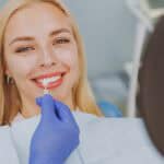 Patient smiling as dentist selects the right veneer color for her teeth.